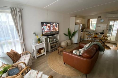 a living room with couches and a flat screen tv at Rosebud Beach Cottage in Rosebud
