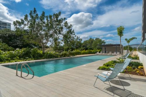 a swimming pool with two lounge chairs next to it at Torre Indico by Casago in Mérida