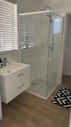a bathroom with a shower with a glass shower stall at Rosebud Beach Cottage in Rosebud