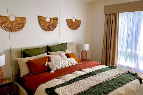 - une chambre avec un grand lit et des oreillers colorés dans l'établissement Rosebud Beach Cottage, à Rosebud
