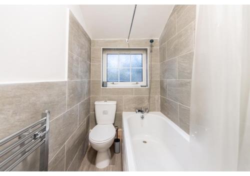 a bathroom with a toilet and a tub and a window at Fresh and Relaxing 1 BD Flat in Manchester