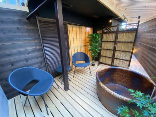 a deck with two blue chairs and a tub at アムール神戸イースト in Honjōchō- Fukae