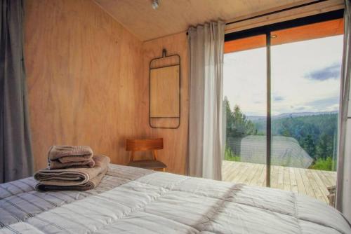 ein Schlafzimmer mit einem Bett und einem großen Fenster in der Unterkunft Casa Las Golondrinas in Cobquecura