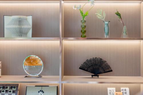 a shelf with various vases and a fan on it at Fortune Land Shenzhen in Shenzhen