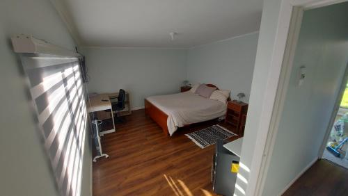 a bedroom with a bed and a desk and a window at Camino de Luna, amplio y cómodo espacio in Valdivia