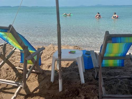 un tavolo e sedie sulla spiaggia con persone in acqua di Pousada Arraial do Cabo - Praia dos Anjos ad Arraial do Cabo