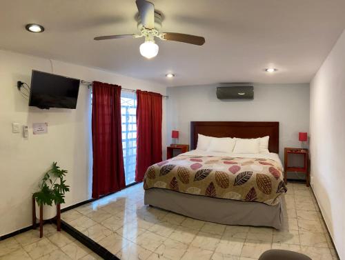 梅里達的住宿－Suites del Sureste - Mérida，一间卧室配有一张床和吊扇