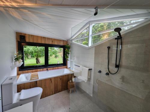 baño con aseo, bañera y ventana en Daylesford - Frog Hollow Estate -THE COTTAGE - enjoy a relaxing and romantic night away in our gorgeous little one Bedroom ROMANTIC COTTAGE under the apple tree with water views, en Daylesford