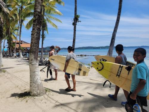 RIVA B&B في بوكاس تاون: مجموعة من الناس تقف على شاطئ يحمل ألواح ركوب الأمواج