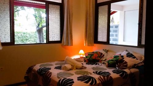 a bed in a room with two windows at Belle Maison F3 in Papeete
