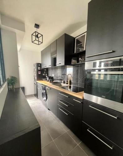 a kitchen with stainless steel appliances and black cabinets at Charme près de Paris, Élégance urbaine in Soisy-sous-Montmorency