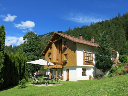 ein Haus mit einem Tisch und einem Sonnenschirm in der Unterkunft Appartement Doris in Schröcken