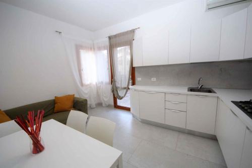 cocina con armarios blancos y encimera blanca en Apartments in Rosolina Mare 33313 en Rosolina Mare
