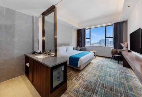 a hotel room with a bed and a flat screen tv at Fortune Land Shenzhen in Shenzhen