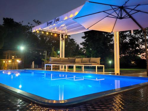 a swimming pool with a couch and an umbrella at HOMETHAI RESORT (โฮมไทยรีสอร์ท) 