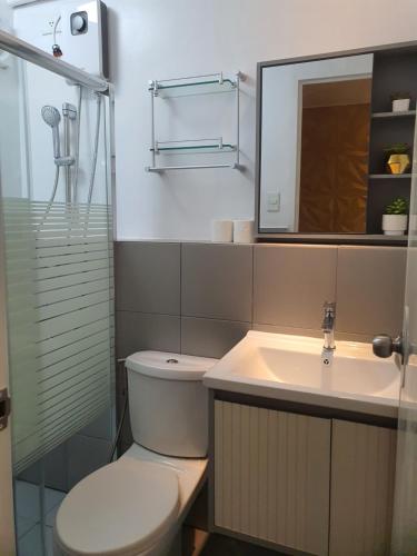 y baño con aseo, lavabo y espejo. en white room 2BR condo in banilad cebu, en Mandaue