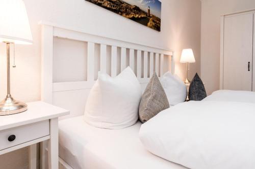 - une chambre blanche avec un grand lit blanc et des oreillers dans l'établissement Norderhoog-Whg-30-1-OG-Wohnung-30, à Westerland