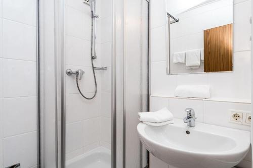 La salle de bains blanche est pourvue d'une douche et d'un lavabo. dans l'établissement Norderhoog-Whg-30-1-OG-Wohnung-30, à Westerland