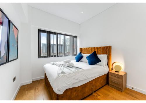 Dormitorio blanco con cama de madera y almohadas azules en Stylish Flat in Centre Hassle Free Peaceful, en Maidenhead