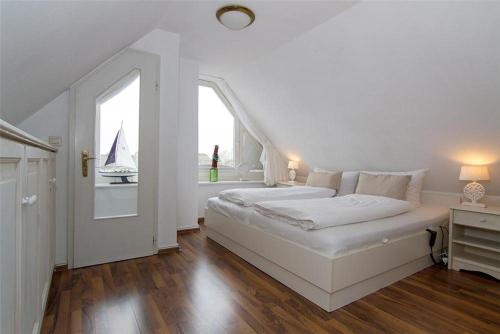 a white bedroom with a large bed and a window at Haus-Seemoewe in Archsum