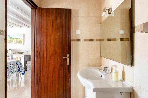 uma casa de banho com um lavatório e uma porta de madeira em AroeiraMIR Villa with private pool and beach em Arieiro