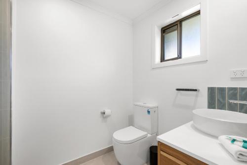a white bathroom with a toilet and a sink at Wilson Executive Apartments in Thomson