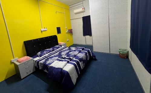 ein Schlafzimmer mit einem Bett in einem gelben Zimmer in der Unterkunft HOMESTAY Kg TOKKU KOTA JEMBAL in Kota Bharu