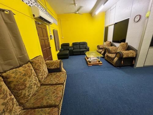 ein Wohnzimmer mit Sofas und einer gelben Wand in der Unterkunft HOMESTAY Kg TOKKU KOTA JEMBAL in Kota Bharu