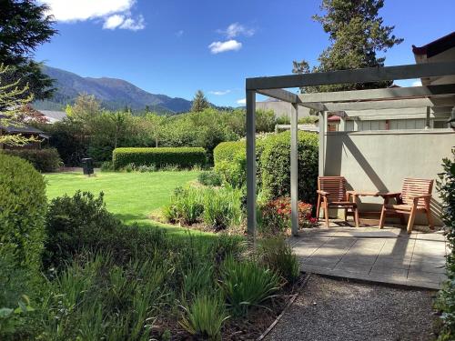 a patio with two chairs and a table in a garden at Hanmer Garden Suites in Hanmer Springs