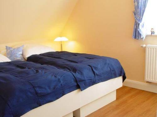 ein Bett mit blauer Decke in einem Schlafzimmer in der Unterkunft  Mare Frisicum 2 in Sankt Peter-Ording