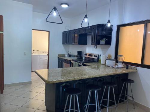 a kitchen with a counter and bar stools in it at Beautiful newly refurbished 2 bedroom 2 Bathroom 2nd floor condo in Tamarindo