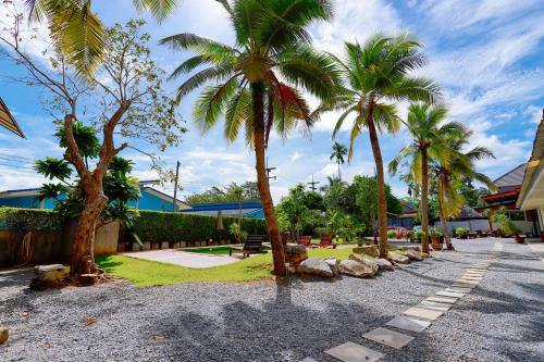 a row of palm trees on a gravel road at Aonang Privacy Resort in Ao Nang Beach