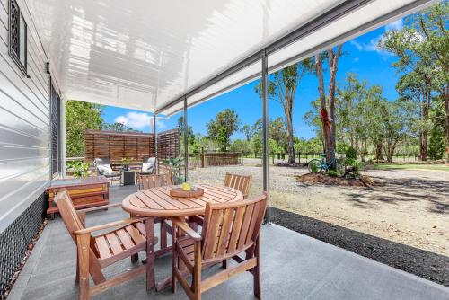 an open porch with a wooden table and chairs at Little Sunshine - Private acreage Guest Home in Hervey Bay