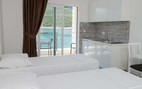 a bedroom with two beds and a kitchen with a view at Apartments Villa Luce in Neum