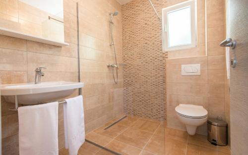 a bathroom with a toilet and a sink and a shower at Apartments Villa Luce in Neum