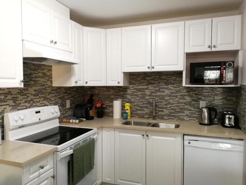 a white kitchen with white cabinets and a sink at A Comfortable 1Bedroom Suit with Seperate Entrance in New Westminster