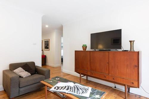 a living room with a couch and a television on a cabinet at Sydney -Cammeray apartment in Sydney