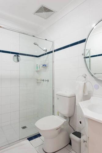 a white bathroom with a toilet and a shower at Sydney -Cammeray apartment in Sydney