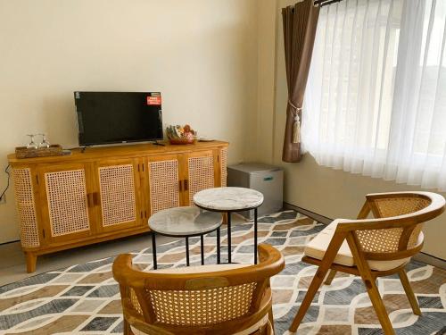 a living room with two chairs and a table and a tv at Ayodya Batur Villa in Kintamani
