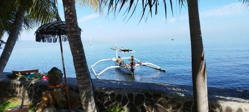 a small boat in the water with palm trees at 1000 Dream Bungalow in Lovina