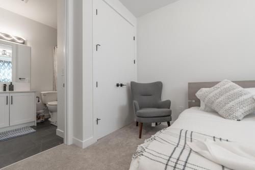 a white bedroom with a bed and a chair at Room 2 of Lovely home, Montgomery downtown Calgary in Calgary