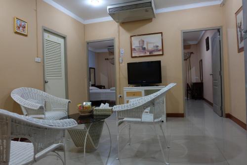 sala de estar con mesa, sillas y TV en PR Place Hotel en Bangkok