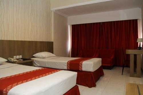 a hotel room with two beds and a chair at University Club (UC) Hotel UGM in Yogyakarta