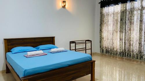 a bedroom with a blue bed with towels on it at Elisha Place Hiriketiya in Dickwella