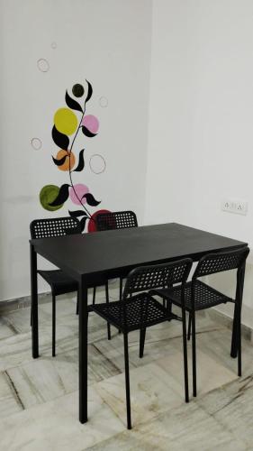 a black table with two chairs and a vase on it at Dumzy's Tombs View in Hyderabad