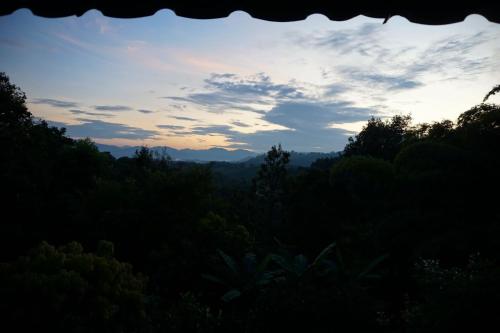 a view of a forest with the sunset in the background at Tafelberg detached bungalow with swimming pool in Chiang Rai