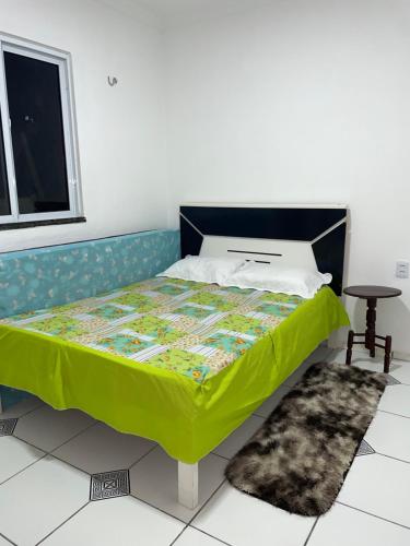 a bedroom with a bed with a green comforter at Apartamento do Walisson in Guaramiranga