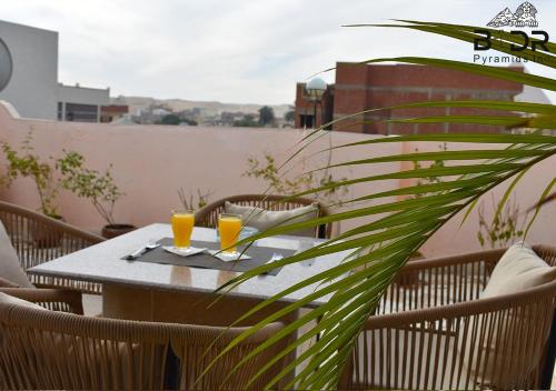 a table with two glasses of orange juice on a balcony at Badr pyramids inn in Cairo