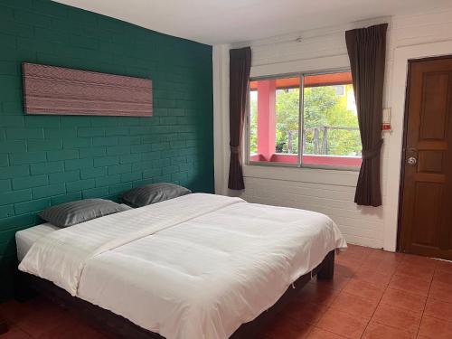 een slaapkamer met een groene muur en een bed bij Red Brick in Chiang Mai