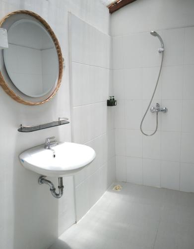Roots Hotel Trawangan في Pawenang: حمام أبيض مع حوض ومرآة